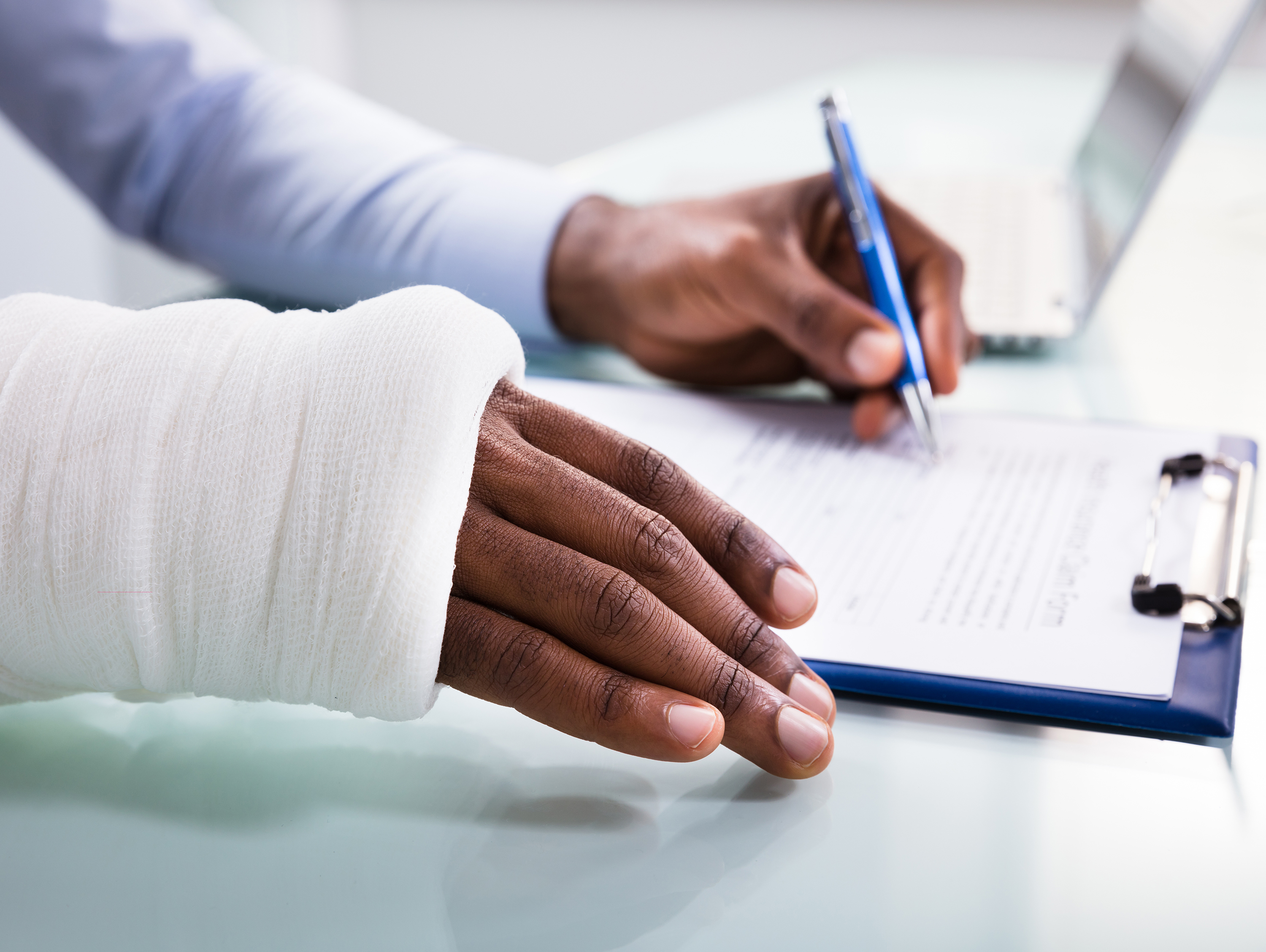 Man with Wrapped Arm Writing on Clipboard