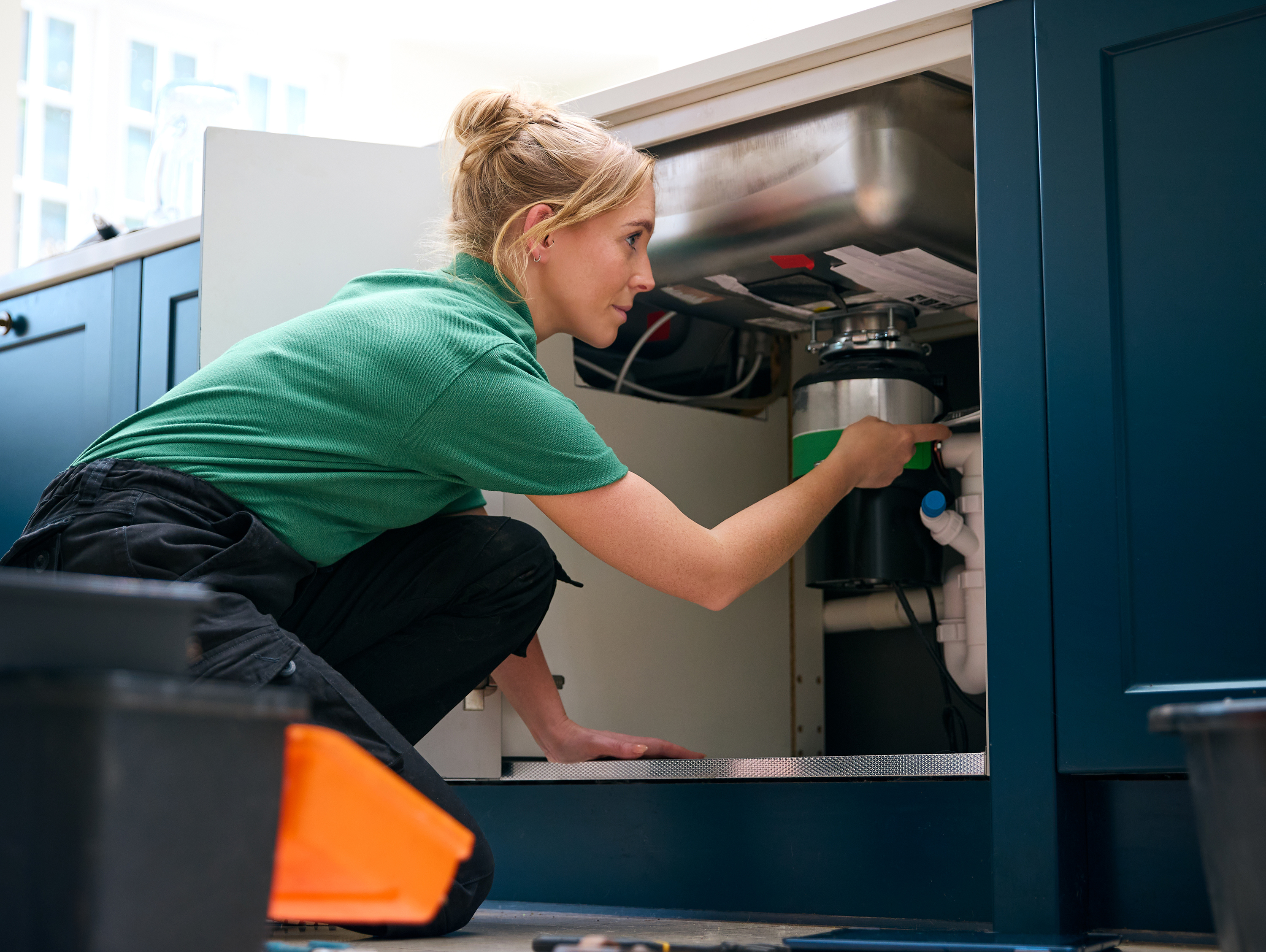 Female Plumber Working Under Sink